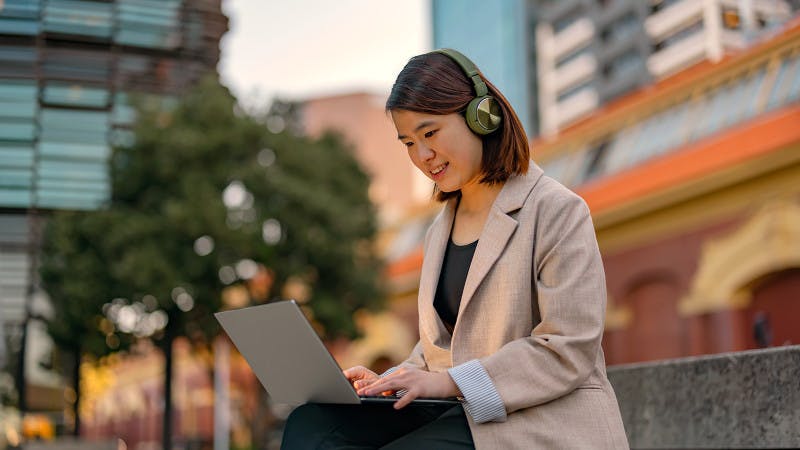 Student on laptop outside with headphones
