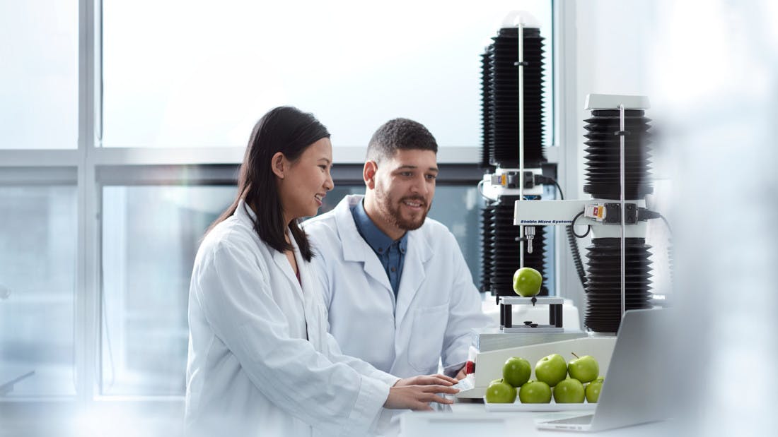 Two international students are in a laboratory and using the equipment to study green apples